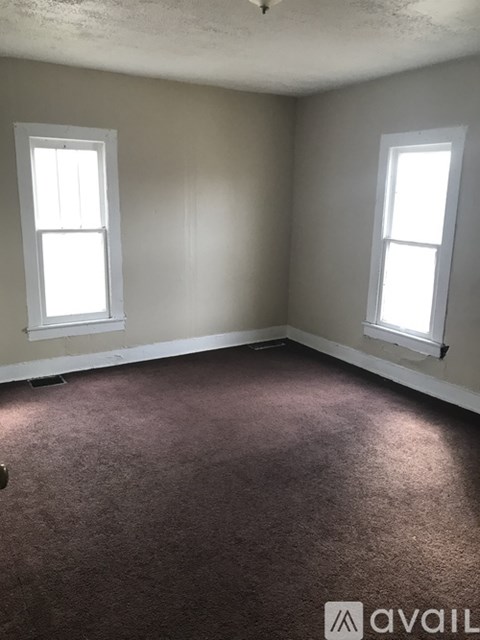 A room with two windows and carpeted floor.