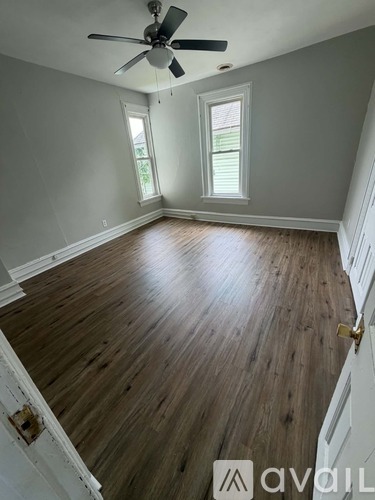 A room with a ceiling fan and a window with blinds.