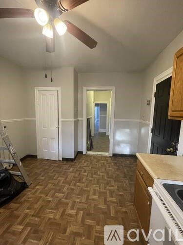 A room with a ceiling fan and a kitchen area with a stove top oven.
