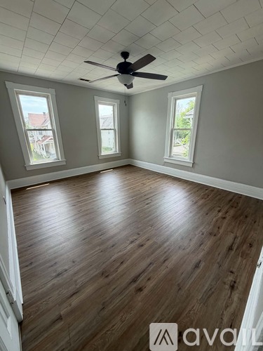 A room with a ceiling fan and wooden flooring.