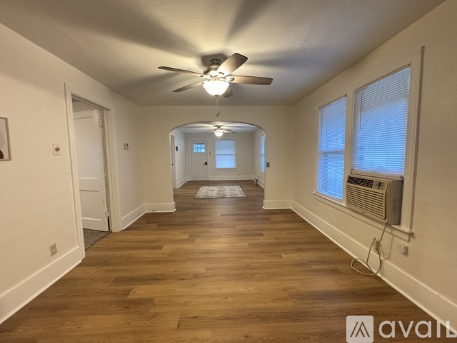 A spacious room with wooden floors and a ceiling fan.