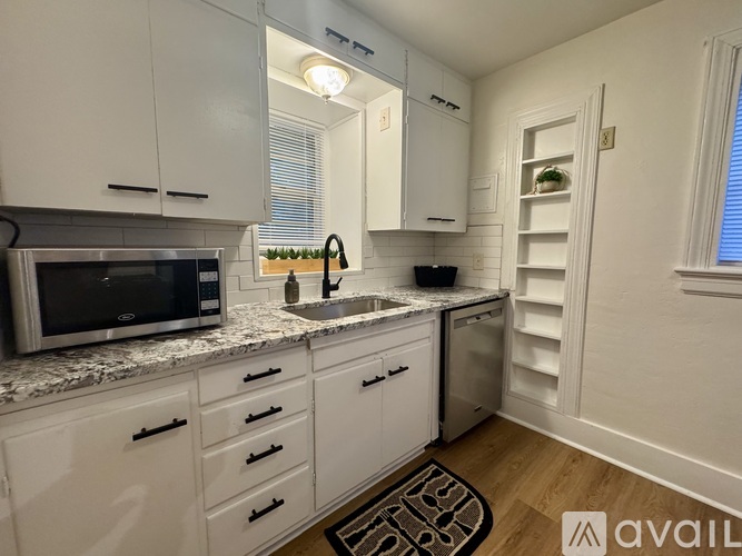 A kitchen with white cabinets and a granite countertop.