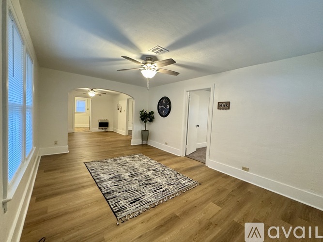 A living room with a rug on the floor and a ceiling fan above.