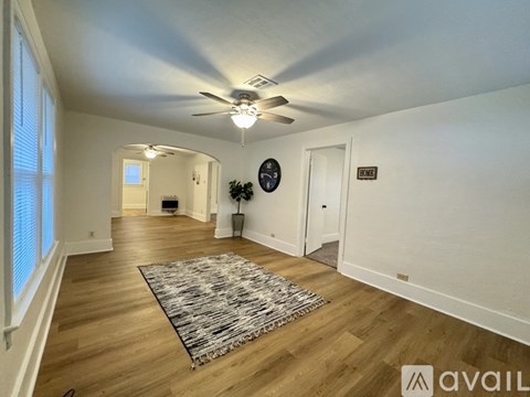 A living room with a rug on the floor and a ceiling fan above.