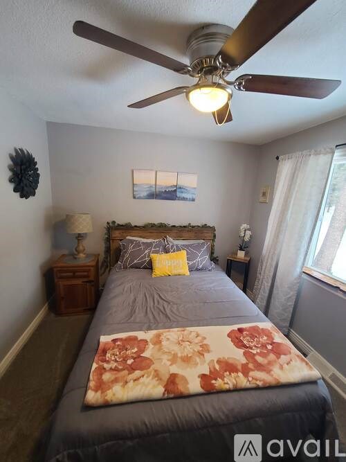 A bedroom with a bed, a ceiling fan, and a window.