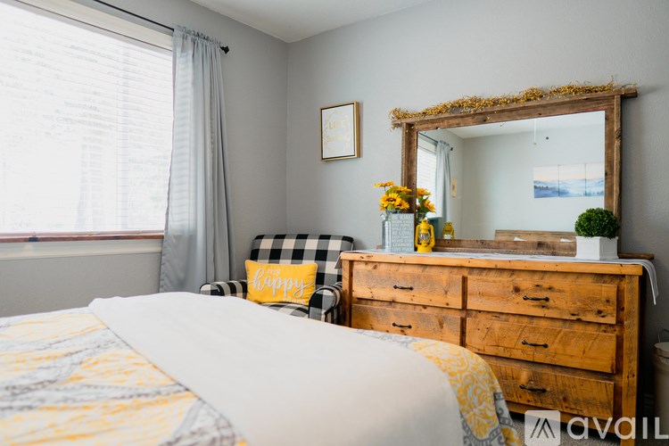 A bedroom with a bed, a wooden dresser, and a mirror with a decorative frame.