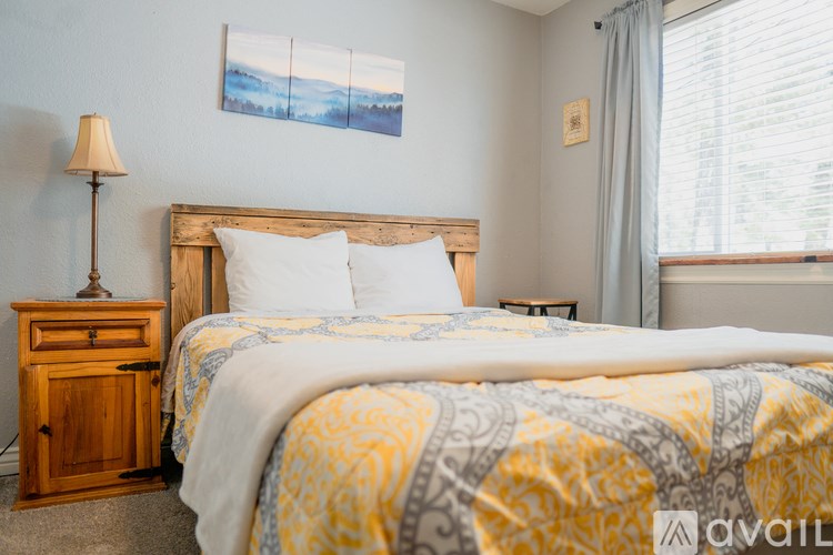 A bedroom with a bed, nightstand, and a painting on the wall.