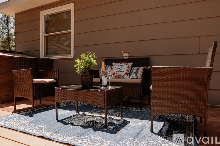 A patio with a table, chairs, and a rug.