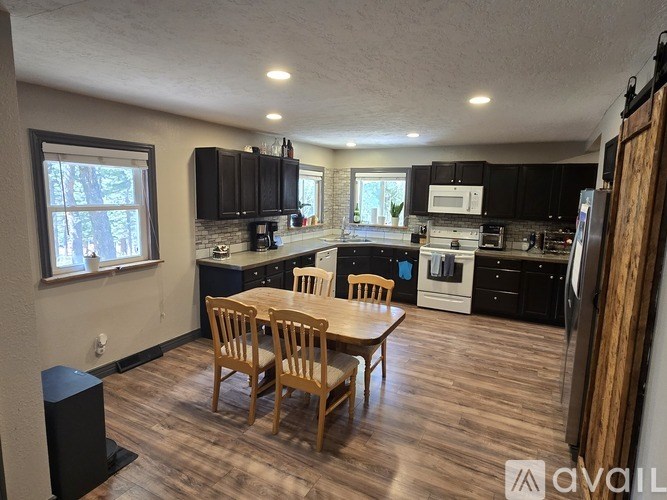 A living room with a black leather couch, a coffee table, a flat screen TV, and a ceiling fan.