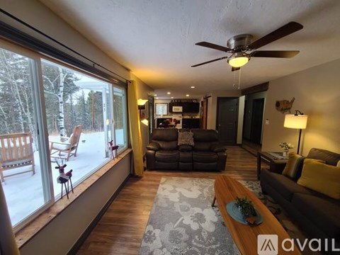 A living room with a brown couch and a ceiling fan.