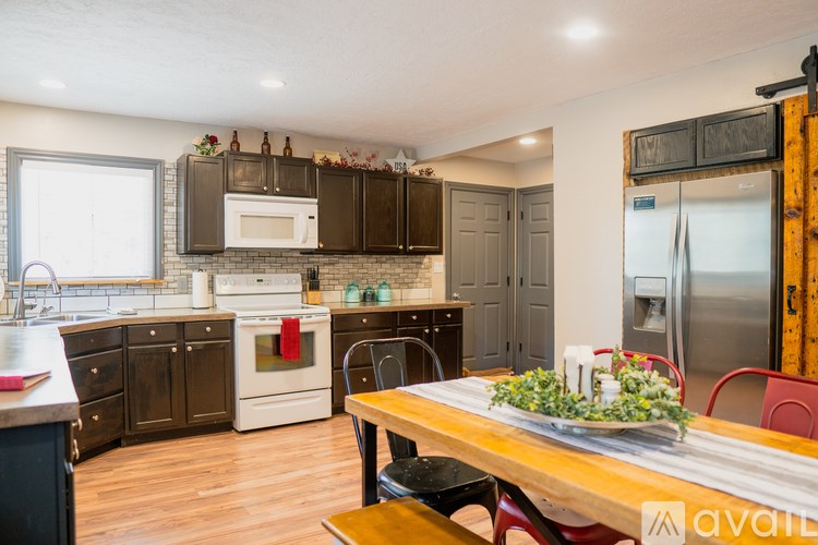 A kitchen with a wooden table and chairs in the foreground and a refrigerator in the background.