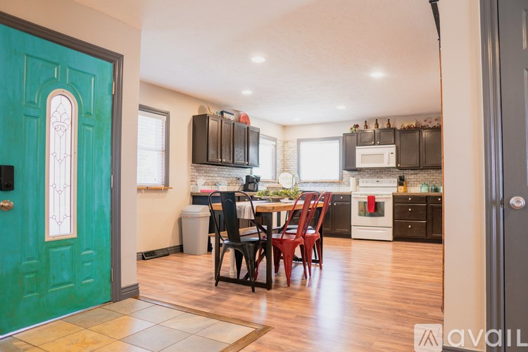 A kitchen with a green door and a dining table with chairs.