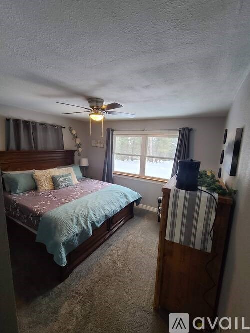 A bedroom with a bed, a ceiling fan, and a window.