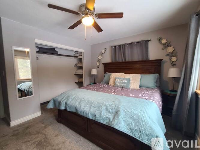 A bedroom with a bed, a ceiling fan, and a window with blinds.