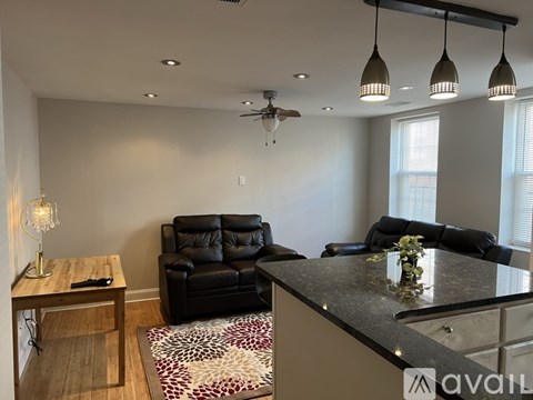 A living room with a black leather couch and a wooden coffee table.