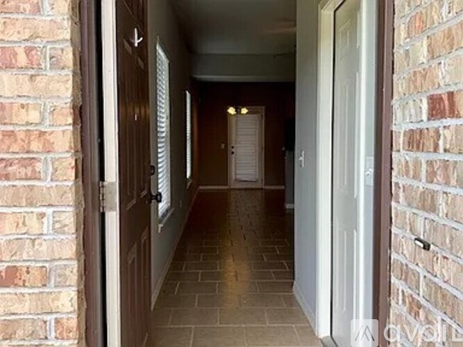 A hallway with a brick wall on the left and a white door on the right.