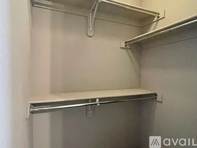 A white shelving unit with three shelves is mounted on a white wall.