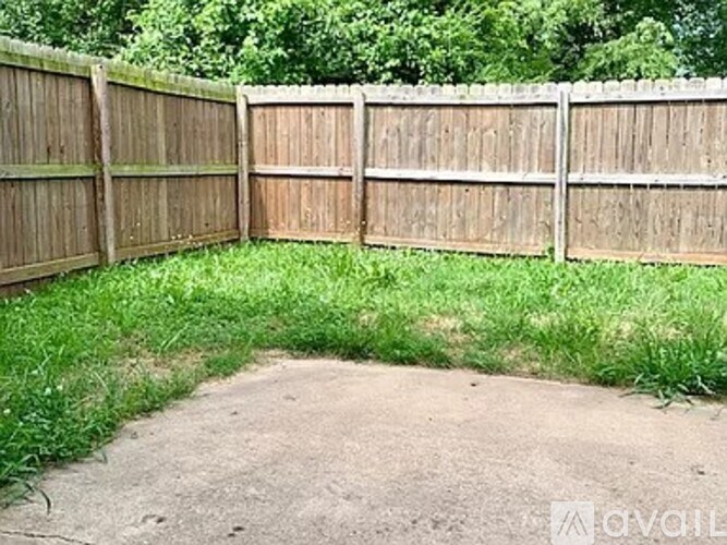 A wooden fence encloses a grassy area with a dirt path leading to it.