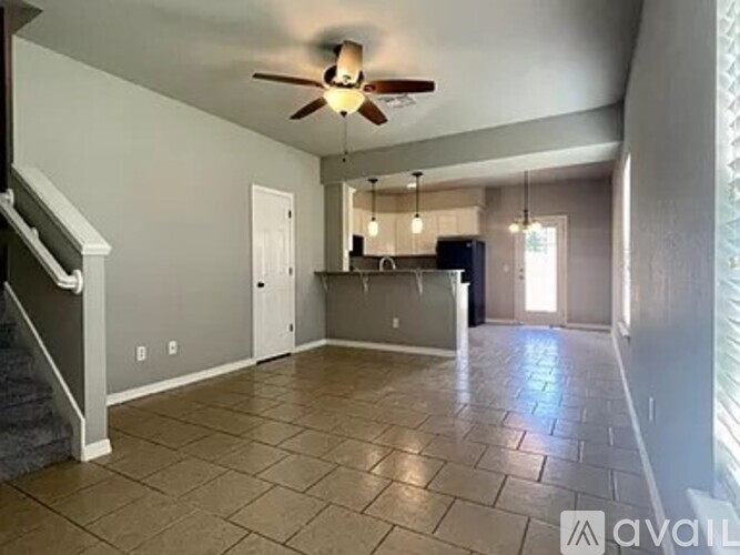 A spacious living room with a ceiling fan and tiled flooring.