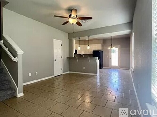 A spacious living room with a ceiling fan and tiled flooring.