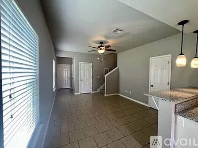 A room with a fan and a counter with a sink.