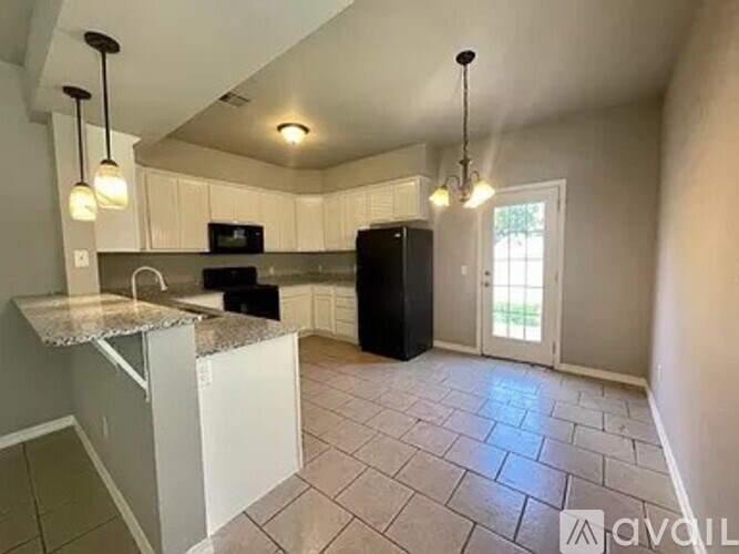 A kitchen with a black refrigerator and white cabinets.