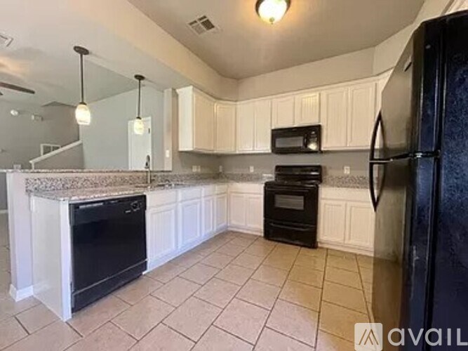 A kitchen with black appliances and white cabinets.