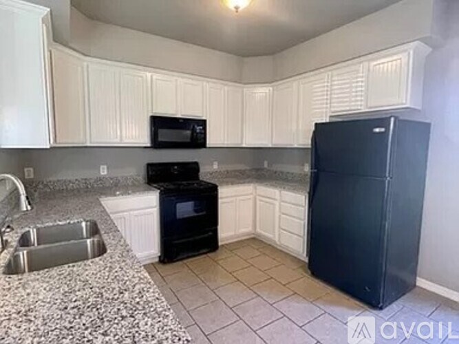 A kitchen with a black refrigerator and white cabinets.