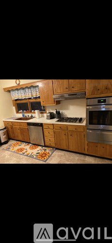 A kitchen with wooden cabinets and a rug on the floor.