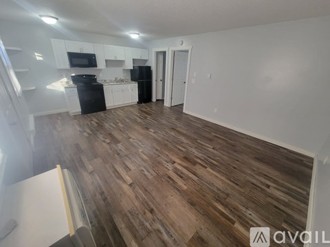 A kitchen with black appliances and wooden floors.