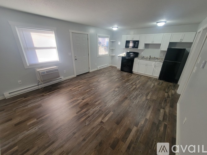 A spacious room with wood flooring and white walls.