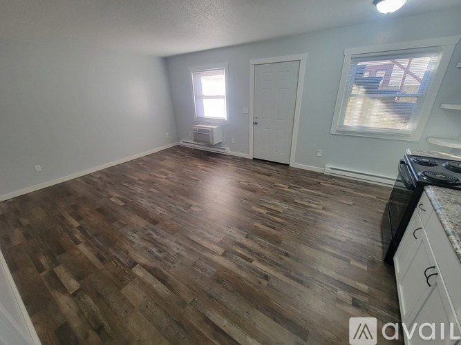 A room with wooden flooring and a window with blinds.