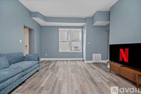 A living room with a blue couch and a television displaying the Netflix logo.