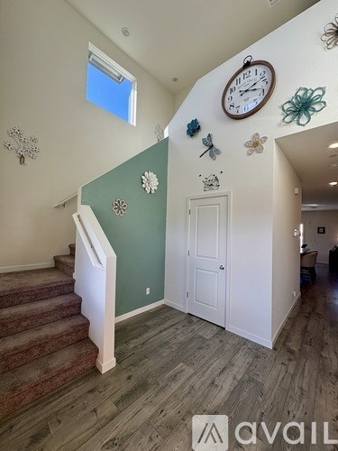 A staircase with a white railing and a green wall with a clock on it.