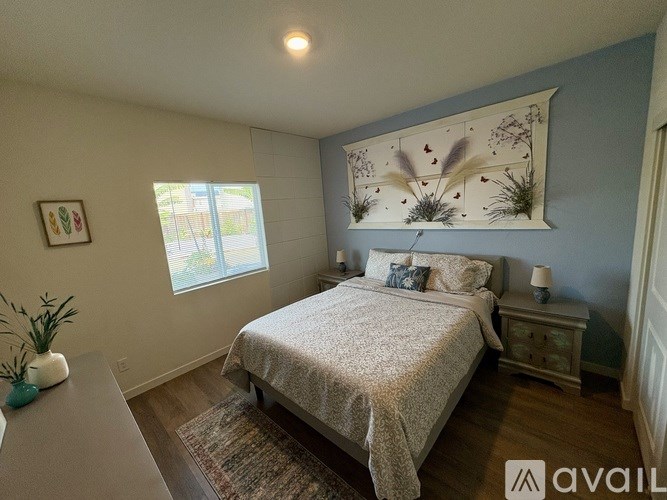 A bedroom with a bed, nightstand, and a window.