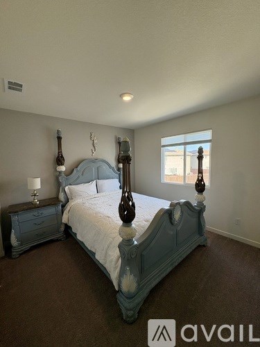 A bedroom with a large bed and a nightstand with a lamp.