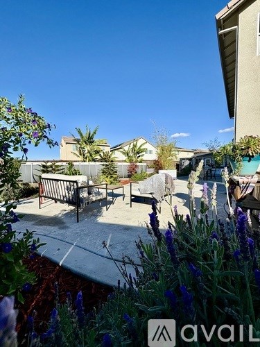 A patio area with a table and chairs surrounded by lavender plants.