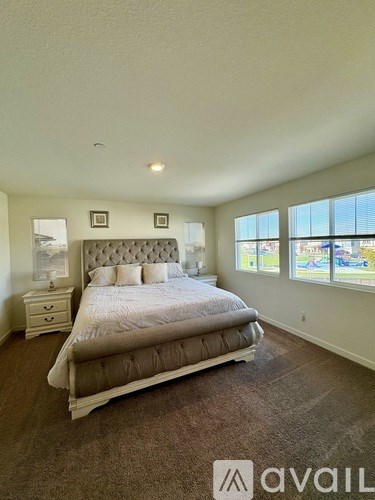 A bedroom with a large bed, nightstand, and window.