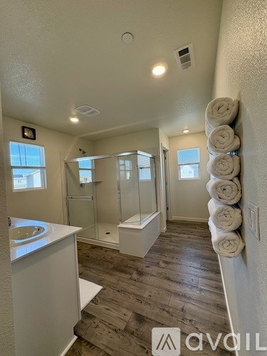 A bathroom with a white sink and a glass shower stall.