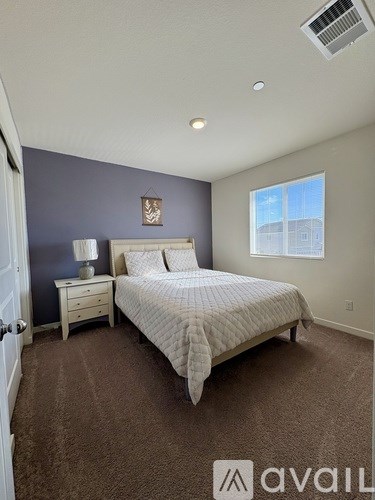 A bedroom with a bed, nightstand, and window.