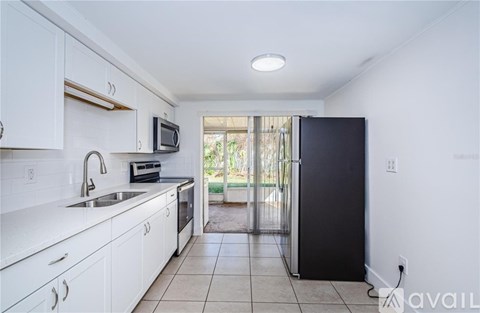 A kitchen with white cabinets and a black refrigerator.