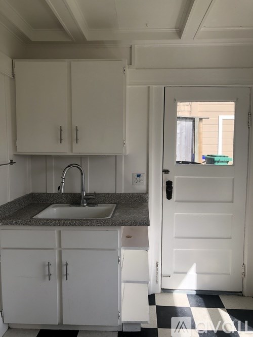 A kitchen with white cabinets and a checkered floor.