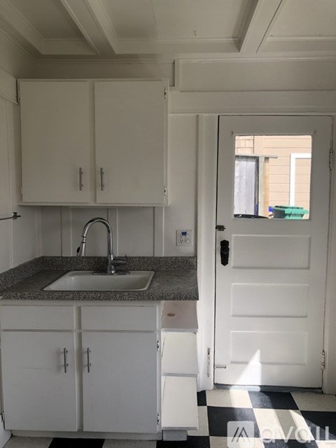 A kitchen with white cabinets and a checkered floor.
