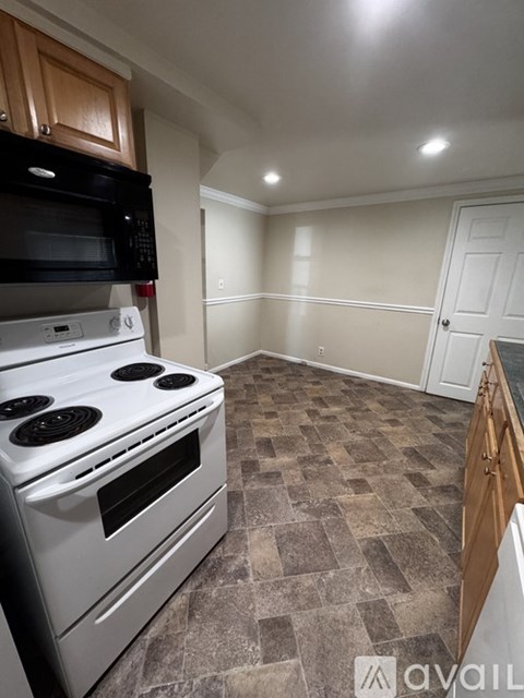 A room with wooden flooring and two windows with blinds.