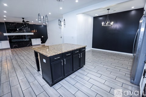 A kitchen with black cabinets and a granite countertop.