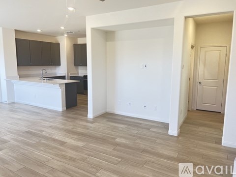 A spacious room with wooden flooring and a kitchen area with a sink and cabinets.