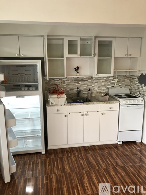 A kitchen with white cabinets and a wooden floor.