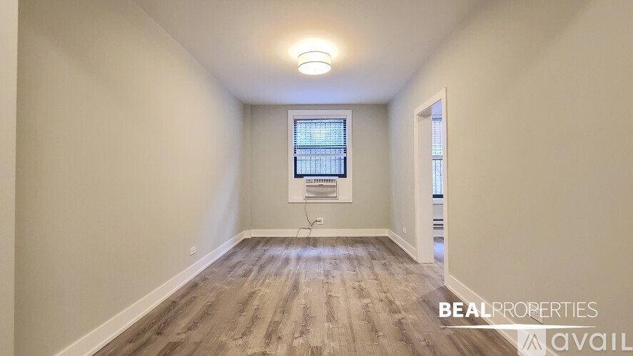 A room with wooden flooring and a window with blinds.