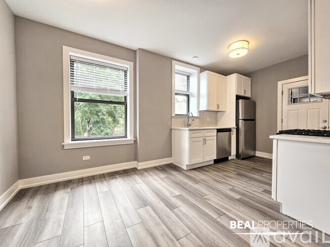 A well-lit kitchen with a refrigerator, sink, and cabinets.