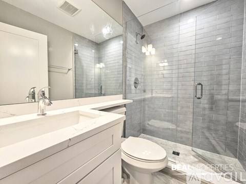 A modern bathroom with a white toilet and a walk-in shower.